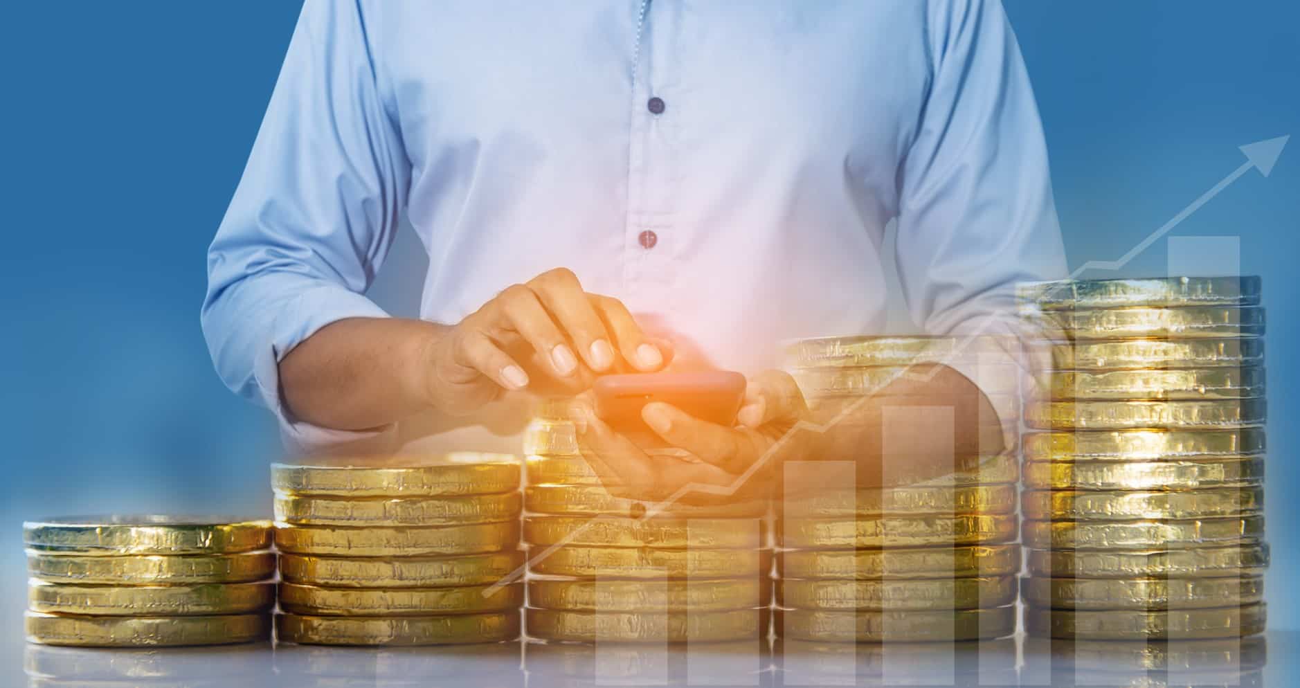 چند سکه طلا به صورت پلهای با یک نفر در بکگراند در حال کار کردن با گوشی خود